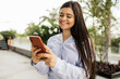 © kleberpicui - Young businesswoman using smartphone in downtown streets near business buildings