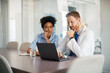 © Drazen - Male doctor and nurse reading medical data on laptop in office.