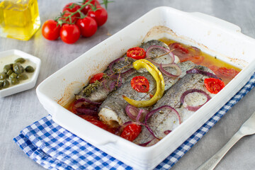 Dish of baked fish trout with vegetables on grey table