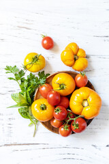 Wall Mural - Raw organic vegetables. The concept of vegan or diet food. Fresh ripe bunch colorful tomatoes, red, yellow on a wooden table. View from above.