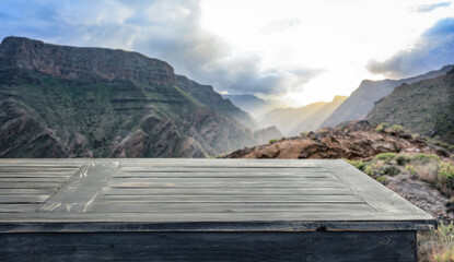 Wall Mural - Empty old wooden table in the autumn afternoon against the backdrop of beautiful mountains and sunset