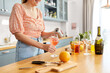 © Syda Productions - drinks and people concept - close up of woman pouring soda from tin can to wine glass and making orange cocktail at home kitchen