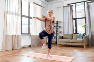 Poster - sport, fitness and healthy lifestyle concept - smiling senior woman exercising on mat at home