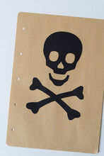 Simple Paper Skull And Crossbones On Brown Paper With Holes