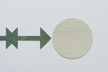 Wall Mural - green paper arrow pointing at a round paper circle with lines