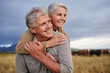 Mature couple embracing and looking happy while bonding outdoors at a farm, carefree and loving. Senior husband and wife having peaceful day in nature, enjoying retirement and relationship