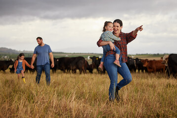 Canvas Print - Happy family bonding on a cattle farm, walking and looking at animals, relaxing outdoors together. Young parents showing child girls how to care for livestock and having fun on exploring nature walk