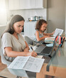 © Kirsten D/peopleimages.com - Mother and daughter being productive with remote work and homework, multitasking at a kitchen table at home. Parent and child serious while paying bills and watching an online education programme