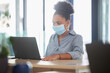 © Alex S/peopleimages.com - Covid, face mask and a black woman working on a laptop in a modern office. Sick businesswoman on the internet at work. College student, online exam and in campus library, protected against the virus.