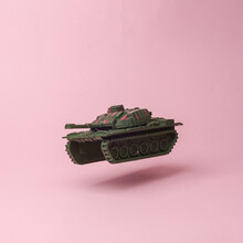 Military Tank Flying In Antigravity On Pink Background With Shadow. Levitation Object In The Air. Creative Minimal Layout