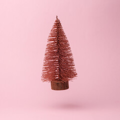 Wall Mural - Decorative Christmas tree flying in antigravity on pink background with shadow. Levitation object in the air. Creative minimal layout