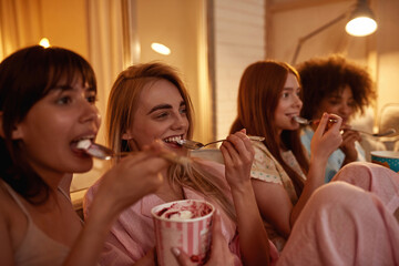 Girls eat ice cream and watch TV or movie at home