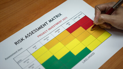 Wall Mural - action of a manager is using ballpoint pen to evaluate on risk assessment matrix of the project inve