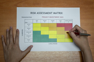 Wall Mural - action of a manager is using ballpoint pen to evaluate on risk assessment matrix of the project inve