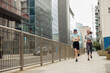 Two athletic women in sportswear are running around the city. Reaching the goal