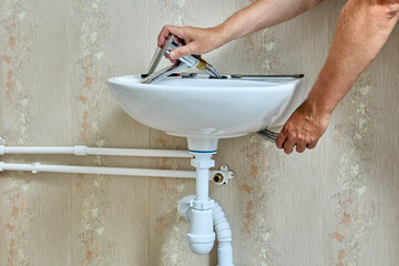 Wall Mural - Plumbing work with home water supply system, plumber installs faucet on sink in bathroom.