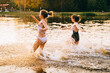 © Iryna - Feeling freedom and fresh air. Two teenager girls in swimsiut friends running on the lake or river on a hot summer day at sunset. Summer cump, happy childhood, active lifestyle concept.