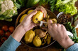 © Konstiantyn Zapylaie - A woman is peeling potatoes. Various fresh vegetables lie on the table. Cooking vegetarian food.