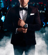© sakkmesterke - Secret agent in bow tie adjusting watch in city night