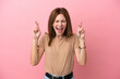 © luismolinero - Young English woman isolated on pink background with fingers crossing