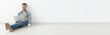 © satura_ - Banner positive young man in casual clothes surfing Internet in search of new housing sitting on floor in empty room. Finding apartment using Internet and laptop. Copyspace.