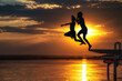 Zwei Freunde kühlen sich mit einem Sprung ins Wasser eines Sees bei Sonnenuntergang ab