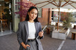 © insta_photos - Young elegant professional leader Asian woman, female executive retail manager supervisor, small business owner wearing suit holding digital tablet standing outdoor looking at camera, portrait.