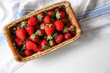 Wicker Basket With Ripe Strawberries And Napkin On White Table, Top View. Space For Text