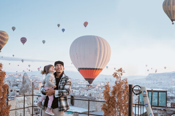 happy family looking at hot air balloon flying around them when visiting cappadocia turkey in winter