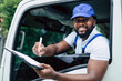 © ztony1971 - Portrait of courier black man in the truck smiling while show the checklist to camera, Optimistic man worker with delivery occupation.