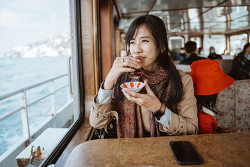 woman sitting on a ferry boat having turkish tea while cruising the bosphorus