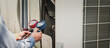 © kunakorn - Mechanic  air conditioner technician is using a manifold gauge to check the refrigerant in the system to inspect and repair the outdoor air compressor.