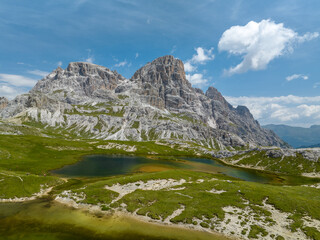 Fototapete - By the lake in the Italian Dolomites on a sunny summer day. People hiking in the hills. 