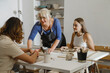 © ninelutsk - Pottery workshop in studio. People working with clay on the table. Adults learning to do ceramic plates. Pottery as hobby and leisure activity
