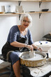 © ninelutsk - Potter making bowl on wheel. self-employed pottery artist in creative studio working with raw clay shaping handmade cup or jar. Cheerful ceramics art teacher recording master class lesson in workshop