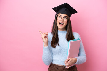 Wall Mural - Young student Brazilian woman wearing graduated hat isolated on pink background intending to realizes the solution while lifting a finger up