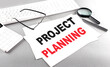 PROJECT PLANNING text on a paper with keyboard, calculator on grey background