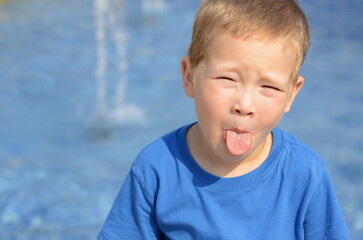 Portrait of a little boy. Emotions of the child, smile, sadness, thoughtful look. Blond boy with blue eyes, close-up, space for text