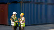 © Ron - Elderly male engineer with safety vest and helmet provides advice and support to young female worker next to blue shipping container. Elder manager is training young staff in a logistics place