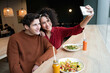 © ADDICTIVE STOCK - Happy couple taking selfie in healthy food restaurant