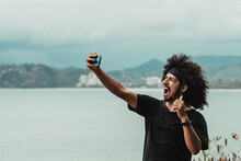 Cheerful Black Man Taking Selfie On Smartphone Against Sea
