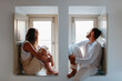 © ADDICTIVE STOCK - Dreamy couple sitting on windowsills and looking out window