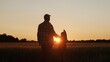 © Acronym - Farmer and his son in front of a sunset agricultural landscape. Man and a boy in a countryside field. Fatherhood, country life, farming and country lifestyle.