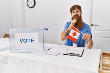 Poster - Caucasian man with long beard at political campaign election holding canada flag serious face thinking about question with hand on chin, thoughtful about confusing idea