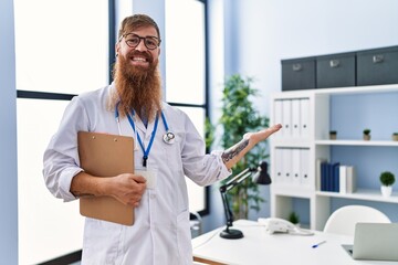 Canvas Print - Young redhead man wearing doctor uniform standing at clinic