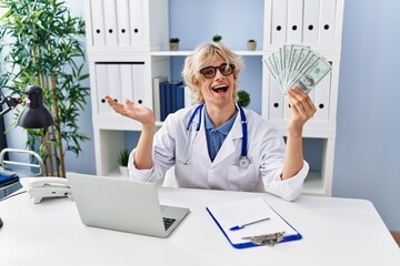 Sticker - Young doctor man holding money celebrating achievement with happy smile and winner expression with raised hand