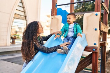 Mother and son playing on slide at park