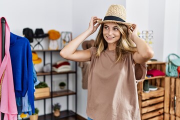 Wall Mural - Young caucasian woman wearing hat shopping at clothing store