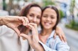 © Krakenimages.com - Woman and girl mother and daughter doing heart symbol with hands at street