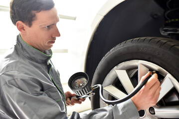 auto mechanic checks the air pressure of a tire in the garage